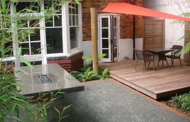 Concrete table, deck and orange sail shade - Carol Whitehead garden design