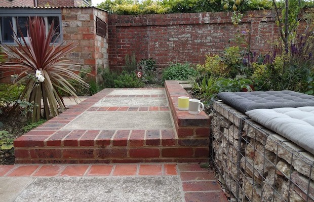 Gabbion seats on recycled concrete patio with red brick edge - Carol Whitehead garden design