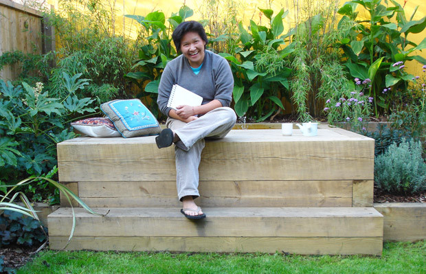 artist sitting on raised wooden deck with sunken pond - carol whitehead garden design